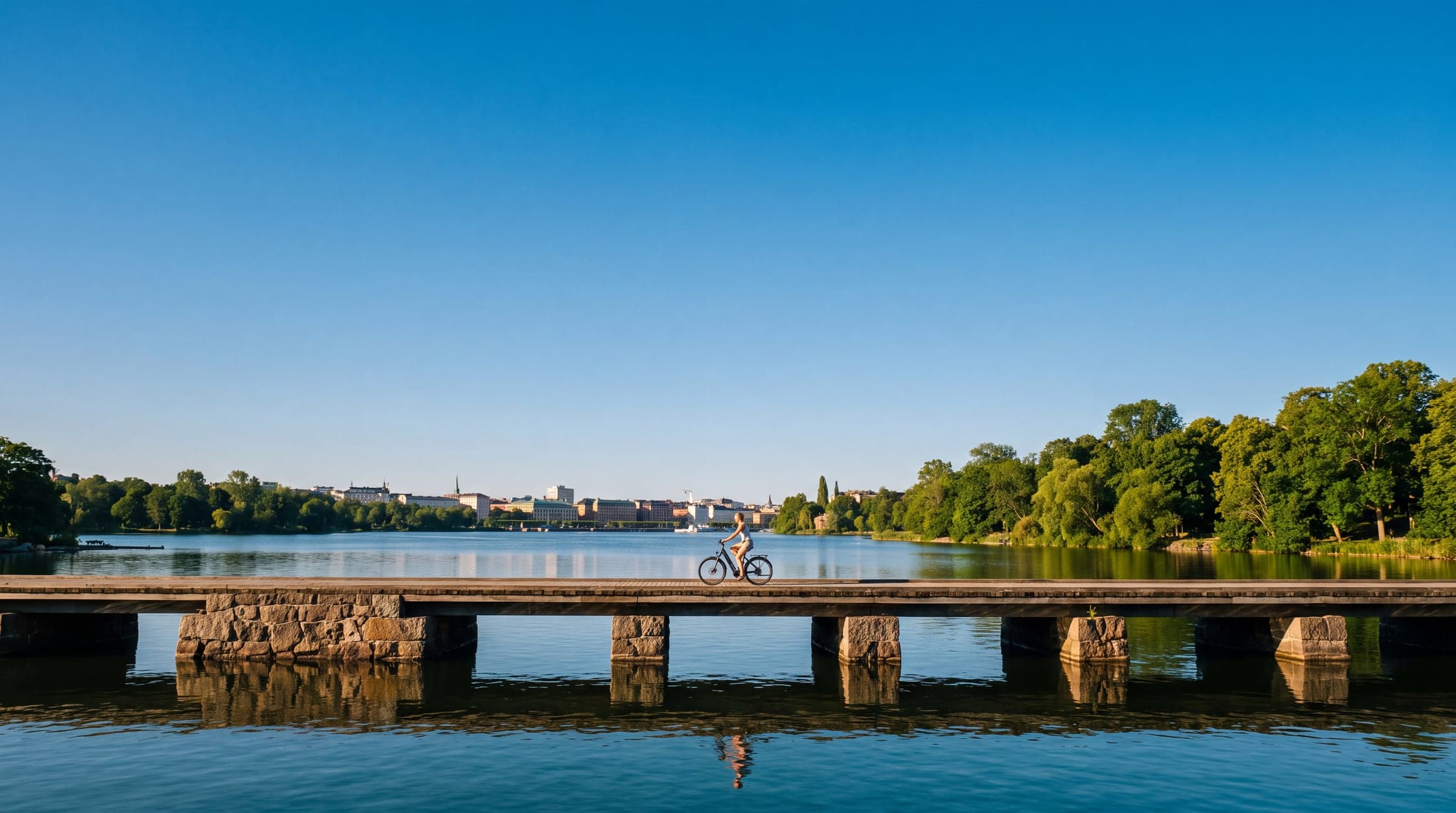 A small rider crosses a long Stockholm bridge over grey water under a pale sky.